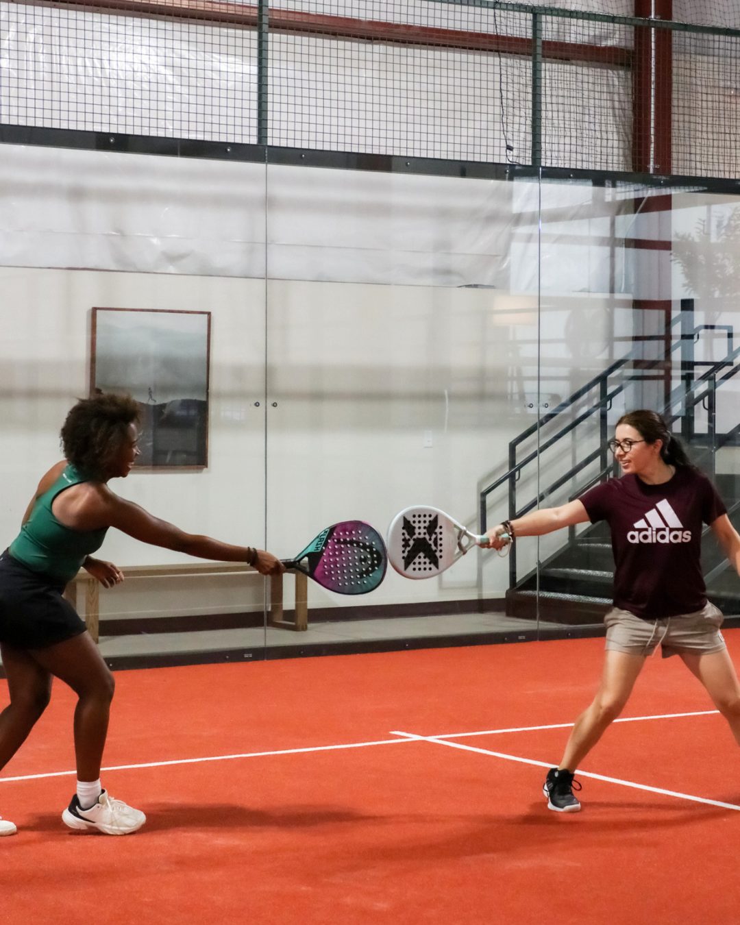 Two players tapping rackets on an Arenna court